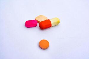 Colorful pills and capsules, including red tablets, isolated on a white background, represent various medications for health and pharmaceutical needs photo