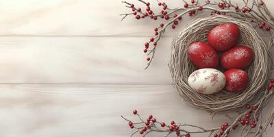 Decorative nest with red and white ornate Easter eggs surrounded by berries on wooden surface photo