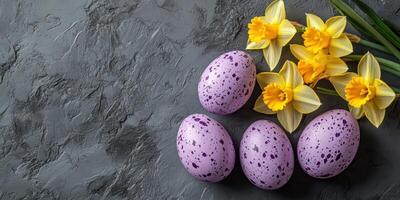 Colorful speckled eggs and bright daffodils on a textured gray surface during springtime celebrations photo