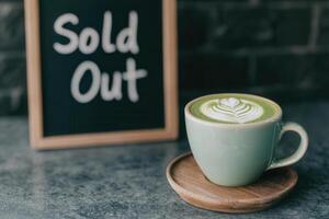 freshly made matcha latte with latte art beside sold out sign photo