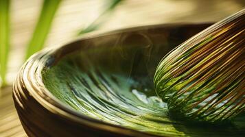 Close up of matcha green tea preparation with whisk and bowl, showcasing vibrant green color and steam photo