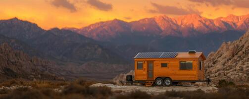 Tiny house with solar panels in mountainous landscape at sunset photo