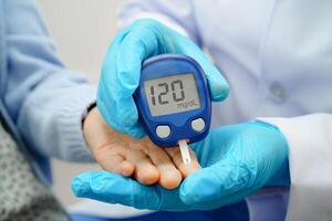 Asian doctor using digital glucose meter for check sample blood photo