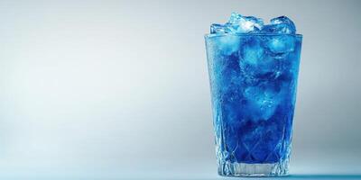 Refreshing blue drink served with ice in a clear glass against a soft background photo