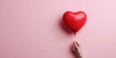 Red heart balloon held against a pink background symbolizes love and affection photo