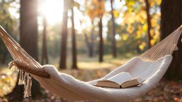 Open book lying on hammock, by golden autumn leaves in serene fall park setting, basking in warm afternoon sunlight background photo