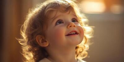 Child with curly hair smiling and looking up in warm light during indoor playtime in the late afternoon photo