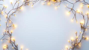 Christmas lights illuminating white frosted leaves creating oval frame on light blue background, perfect for winter holidays greeting card photo