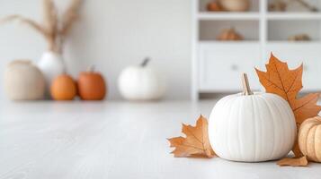 White and orange pumpkins with autumn maple leaves and cozy thanksgiving atmosphere on light wooden table copy space for text photo