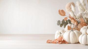 White and orange pumpkins with autumn maple leaves and creating cozy thanksgiving on light wooden table copy space for text photo