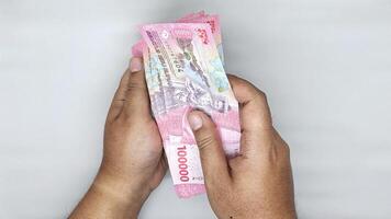 two hands counting Indonesian banknotes in the 100000 rupiah photo
