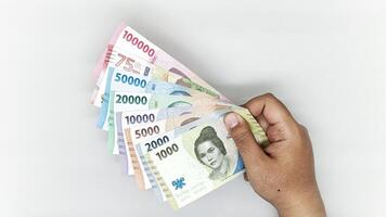 hand holding a collection of Indonesian banknotes in denominations 1000, 2000, 5000, 10000, 20000, 50000, 75000, 10000 rupiah photo