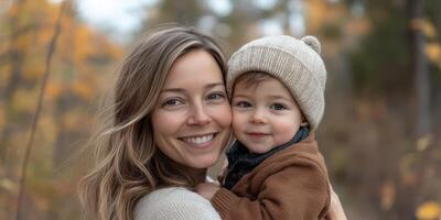 Smiling woman holds child in autumn forest, showcasing warmth and connection in a beautiful outdoor setting photo