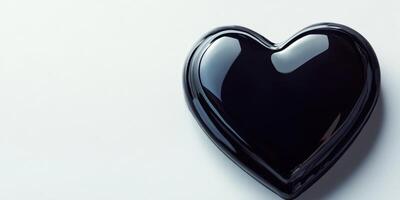 Dark glossy heart shape resting on a light surface creating a contrast in colors and textures photo
