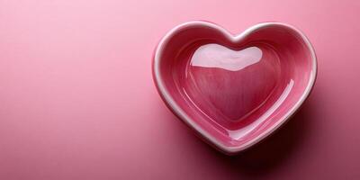 Heart-shaped ceramic bowl on a smooth pink surface with glossy finish reflecting light photo