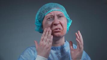 Woman, victim of an accident or abuse, with visible bruises, cuts, and a missing front tooth, wears blue hospital gown. She looks into camera, expressing pain and recounting the traumatic incident. video