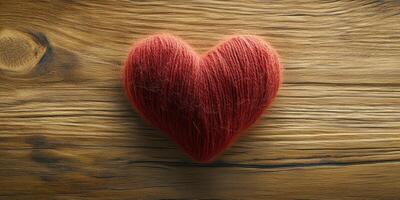 Crafted heart shape made of red yarn placed on a rustic wooden surface photo