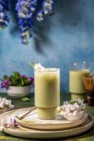 Refreshing iced matcha latte beverage garnished with delicate white flower and mint, served in elegant glass on stylish plates photo