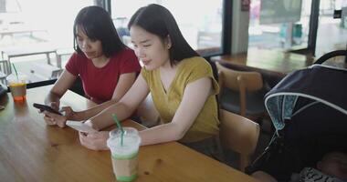 Handheld high angle view shot, Two siblings are having fun playing with their smartphones while sitting at a table in a coffee shop. Family enjoying happy time together. video
