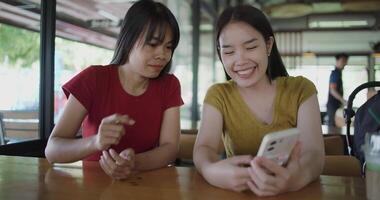 Handheld selective focus shot, Two siblings are enjoying online shopping together on smartphone while sit at a table in a cafe. Family enjoying time together. Happy lifestyle. video