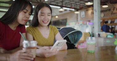 Handheld selective focus shot, Two siblings are enjoying online shopping together on smartphone while sitting at a table in a cafe. Family enjoying time together, Happy lifestyle. video