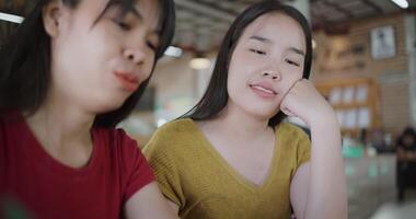 Handheld selective focus shot, Two siblings are enjoying online shopping together on smartphone while sitting at a table in a cafe. Family enjoying time together. Happy lifestyle video