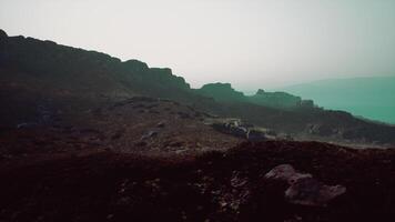 A view of a rocky mountain with a body of water in the distance. mountain path video