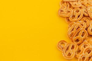 Pretzels scattered on a bright yellow surface for a vibrant snack display photo