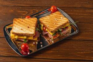 Grilled cheese with ham, spinach, and tomatoes served on a tray photo