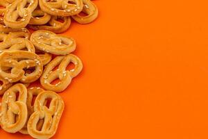 crujiente pretzels rociado con sésamo semillas en brillante naranja superficie foto