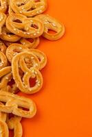 Crispy pretzels arranged on a vibrant orange background for a snack appeal photo