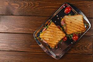 Grilled ham and cheese sandwich with spinach and tomatoes on toast photo