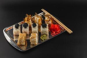 Sushi platter with assorted rolls and garnishes served on a metal tray photo