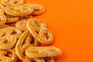 Crispy pretzels scattered on vibrant orange background photo