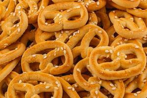 Savory pretzels sprinkled with sesame seeds piled high in a warm setting photo