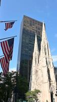 New York City, USA, August 14, 2024. The gothic St. Patrick's Cathedral in a static vertical shot. It is striking in comparison to the modern skyscrapers surrounding it and the American flags. video
