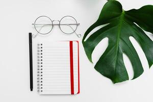 open red notebook with pencil and glasses. school notebook on white background, spiral notepad on table photo