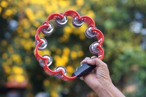 Close up hand hold the tambourine. Concept, playing musical instrument. Shake for the rhythm of music and songs for entertainment. photo