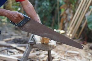 Carpenter hand is cutting wood by saw. Concept, tool for cutting. Carpentry , woodwork and construction work tool. Carpentry. use for cutting wood. Handsaw for carpenter. photo