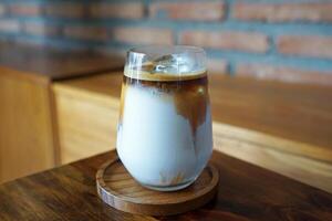 Close up glass of iced dirty Latte coffee on wooden tray table photo