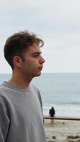 Boy Looks With Neutral Expression Towards The Ocean On A Gloomy Day video