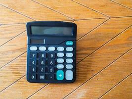 Black calculator on wood grain background. Perfect for finance, accounting, or education concepts. Clean, simple design ideal for websites, blogs, and presentations. photo
