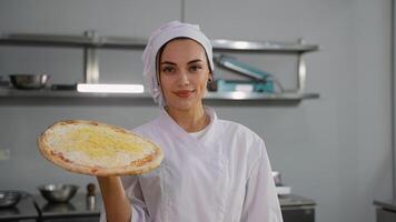 Smiling chef presenting uncooked cheese pizza in kitchen video