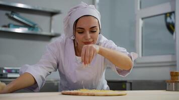 Female chef adding cheese to pizza with focus video