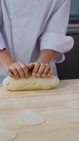 Chef kneading dough with flat circles on wooden table for Dumplings video