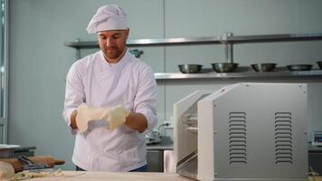 Professional chef in a white uniform using a dough sheeter machine video