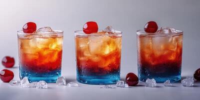 Colorful layered drinks with cherries served in clear glasses on a smooth surface photo