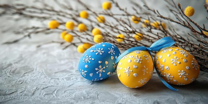 Colorful decorated Easter eggs placed next to twigs with yellow flowers on a textured surface during spring photo