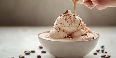 Scoop of vanilla ice cream drizzled with chocolate sauce amidst coffee beans on a wooden table photo