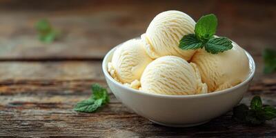 Creamy vanilla ice cream scoops in a bowl garnished with fresh mint on a rustic wooden table photo